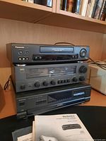Stack of Panasonic PV-7661 CD player on top, NAD 7020 stereo receiver in the middle, and Technics SL-PD687 CD changer at bottom with user manuals.