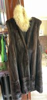 Front view of sleeveless dark brown fur coat with separate light-colored fluffy fur collar draped on top