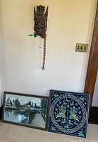 Photo showing the entire lot with the wood mask hanging on the wall above the two framed art pieces leaning against the wall.