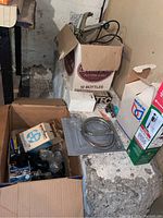 Photo showing boxes with multiple plumbing parts including flexible shower hose, hardware valves, faucet components and packaging boxes.