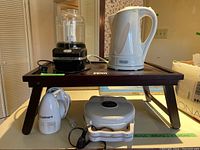 Lot of small kitchen appliances on wooden bed tray. DeLonghi kettle, Kitchenaid chopper, Cuisinart hand mixer, Philips waffle maker visible.