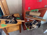 Photo showing several metal and wooden hand planers placed on a small wooden table alongside a wooden yardstick and other tools.