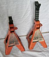 Front view of two orange MotoMaster axle/jack stands with labels showing capacity and brand