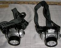 Two black and silver LED headlamps featuring adjustable black/grey headbands with 'LED HEADLIGHT' text.