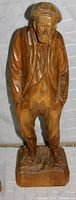Photo of one wooden figurine of old man carved by Paul Caron, showing detailed carving and natural wood finish.