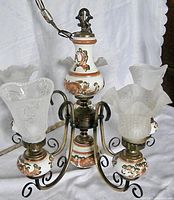 Front and side views of the 5-light chandelier showing the decorative ceramic stem, metal arms, and frosted glass dome shades with floral embossing.