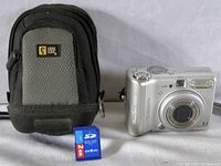 Canon PowerShot A510 camera, Case Logic branded padded carrying case, and 2GB SD card on white surface.
