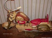 Side view of handcrafted wooden Harley Davidson motorcycle model showing natural wood and red painted details, movable parts including handlebars and kickstand.