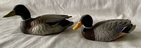 Pair of vintage mallard duck decoys side by side on fabric background