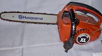 Front view of the Homelite XL chainsaw showing the 14-inch Husqvarna branded guide bar with chain attached to an orange chainsaw body.