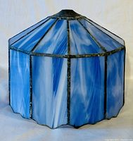 Close up front view of a blue Tiffany style stained glass lamp shade showing the octagonal shape and scalloped bottom edge.