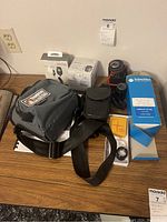 Overview of various cameras, lenses, boxed lenses, camera bags, lens cases, and accessories on a table.