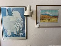 Two framed prints mounted on wall: left is blue-tone figure study, right is Mt Fuji color print