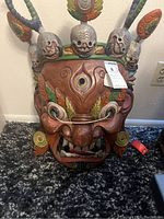 Front view of the large painted Mahakala mask with detailed facial features and skull-adorned crown.