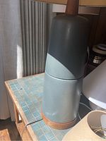 Tall grey-blue ceramic table lamp body without shade on tiled table