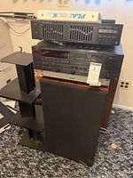 Receiver and equalizer stacked on speaker stand with one speaker in view