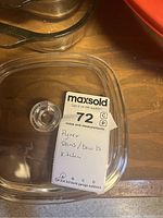 Photo showing a clear square Pyrex lid with a round handle and auction label citing Pyrex pans and bowls
