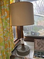 Full view of lamp on windowsill, showing shade, stem and base.