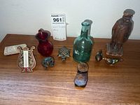 Collection of small decorative trinkets displayed on a wooden surface including glass bottles, enamel birds, wooden figurines, and miniature chair.