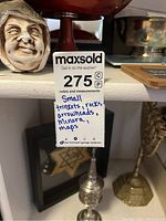 Photo showing decorative head sculpture, metal candle holders including menorah, framed Star of David art, and red bowl on shelf.