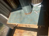 Close top-down view of green square tile inlay on table surface with wood border