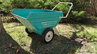 Side view of teal Jackson Deluxe Cart metal wheelbarrow showing model label and wheels