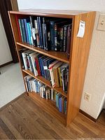 Front view of three-shelf bookcase loaded with books.