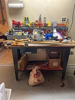 Workbench with assorted tools and storage bins on and beneath it