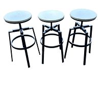 Set of three black metal bar stools with round seats, viewed from front angle.