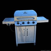 Front view of Char-Broil 4-burner propane gas grill with side burner and side table, showing four control knobs, lid with temperature gauge, and double-door storage cabinet below.