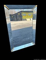 Front view of the rectangular beveled glass mirror showing gold-tone corner accents.