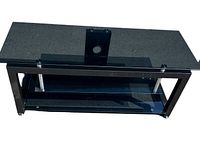 Front angled view of black tempered glass TV stand with metal frame and chrome supports. Shows main top shelf, lower glass shelf, and TV mounting bracket.