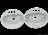 Photo of two white oval china basins side by side showing three faucet holes and overflow.