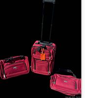 Three-piece red suitcase set including an upright rolling suitcase with handle and two carry bags