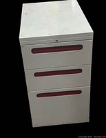 Front view of the white metal 3 drawer file cabinet showing red drawer handles and visible light scratches.