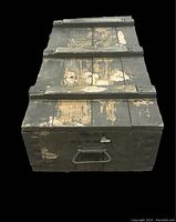 Top view of vintage military wooden chest showing worn green paint and stenciled text PG-15 P Orig S-40-54 on the front side with a central metal handle.