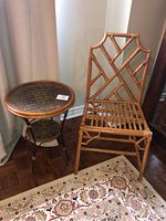 Rattan chair with decorative geometric back and woven seat beside a circular side table with a woven top and metal legs.