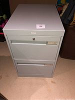 Front view of the gray metal filing cabinet showing two drawers with horizontal handles, Cole branding, and key lock on top drawer.