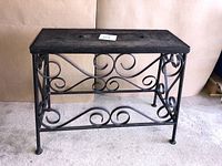 Black heavy iron plant stand with scrollwork and rectangular top shown from front