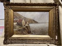 Full view of oil painting depicting coastal village scene and ornate gilded frame