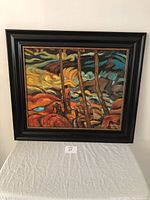 Framed signed oil painting viewed frontally on a white cloth surface