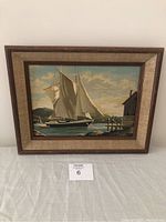 Front view of framed oil painting showing sailboat on water with dock and building.