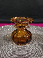 Front view of the amber glass sack vase with ruffled rim, showing bulbous and rounded sack shape and ornate undulated edge at the rim