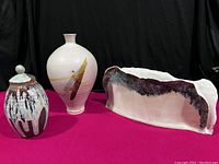 Photo showing all three pottery items together on a red surface against a black background.