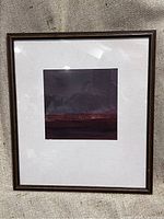 Full view of framed abstract artwork showing the dark wood frame and white mounting paper.