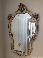 Front view of the vintage wall mirror showing full ornate Rococo-style frame in cream and gold tones.