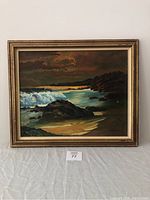 Full front view of framed oil painting showing the seascape scene with waves, rocks and sky at dusk.