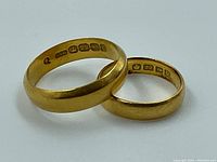 Two yellow gold wedding bands side by side showing exterior profile and inner hallmarks