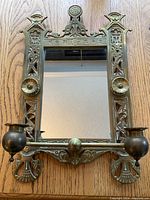 Front view of entire brass mirror and both candle holders lying flat