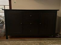Front view of IKEA Hemnes credenza showing two doors and three drawers in a dark wood finish.